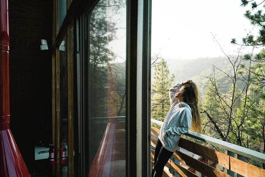 Side View Of Young Woman With Hand In Hair Standing On Balcony In Log ...