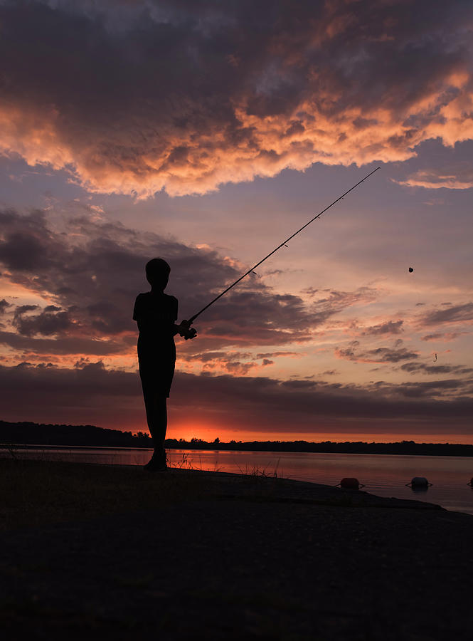 Silhouette Of A Boy Fishing On The Edge Of A Lake At Sunset. Photograph by  Cavan Images - Fine Art America