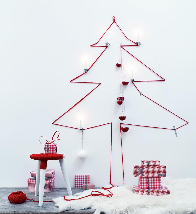 Silhouette Of Christmas Tree Made From Red Wool On Wall Above Stool Wrapped In Yarn Photograph by Andreas Hoernisch