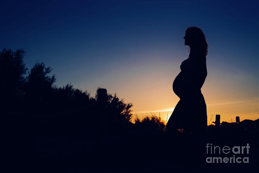 Silhouette of pregnant woman at sunset with solid color background. Photograph by Joaquin Corbalan