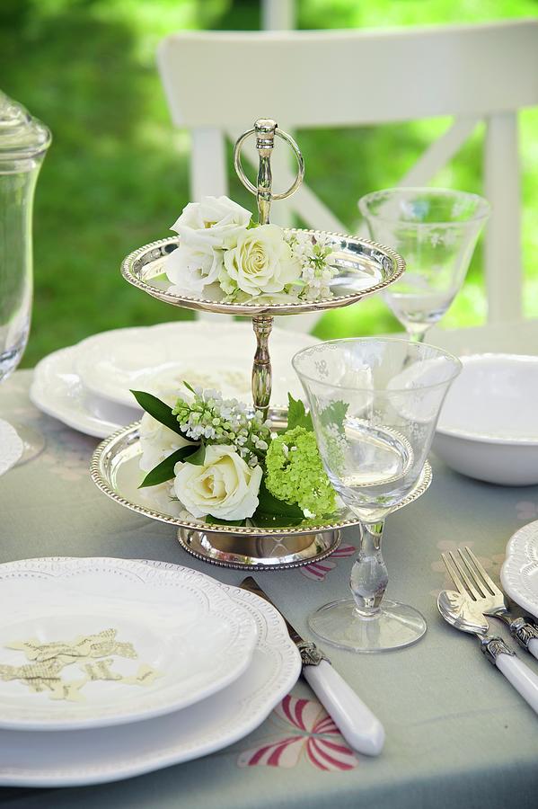 Silver Cake Stand Decorated With White Flowers On Table Set For Wedding Photograph by Winfried Heinze