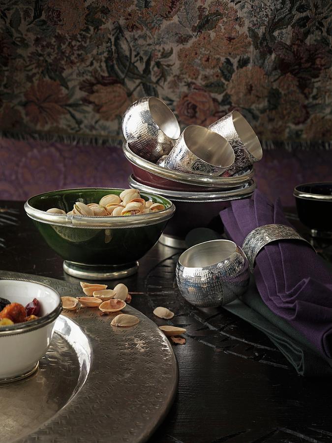 Silver Serviette Rings, Serviettes And Bowls With Pistachios On A Dark Table Photograph by Biglife