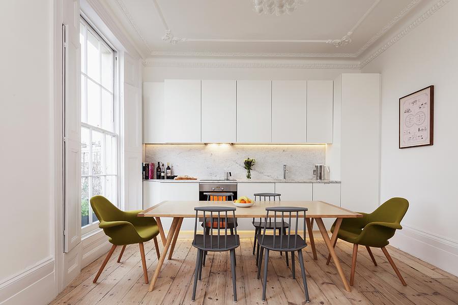 Simple, White Fitted Kitchen In Renovated Period Apartment With Lattice Window, Wooden Floor And Retro-style Dining Area Photograph by Simon Maxwell Photography