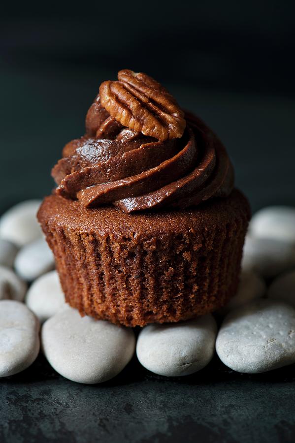 Single Chocolate Cupcake With Pecan Nut On Pebbles Photograph by Magdalena Hendey