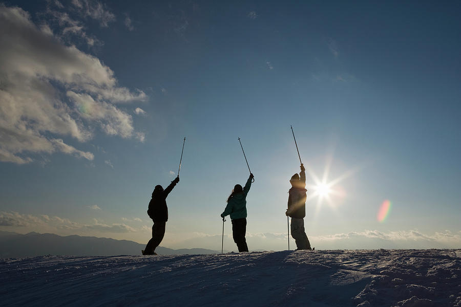Skiers Raising Poles On Mountain Photograph by Michael H