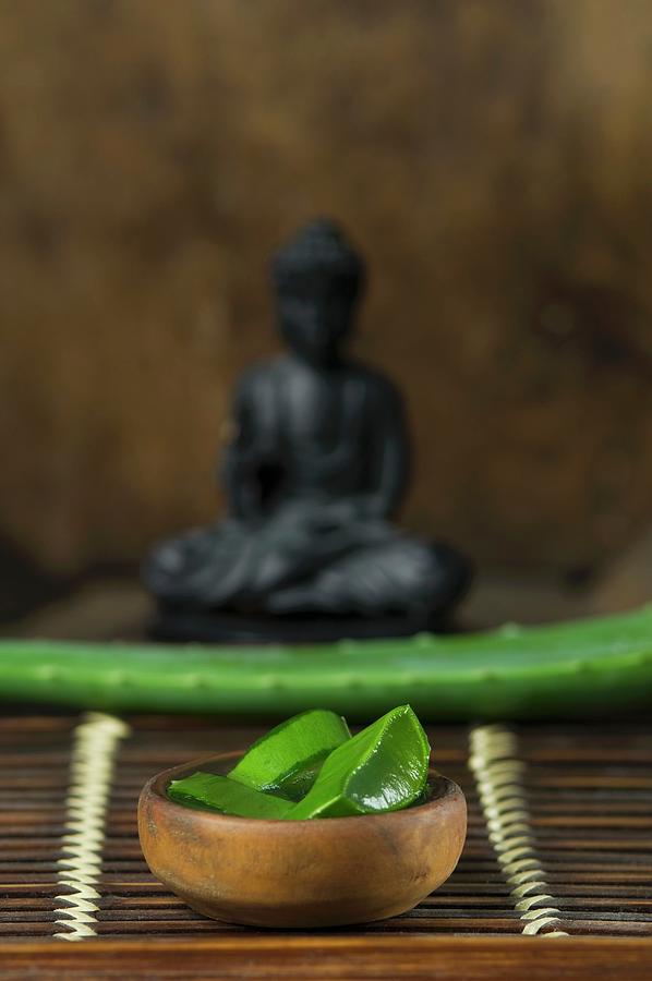 Sliced Aloe Vera Shoots In Front Of A Buddha Figurine Photograph by Sass, Achim