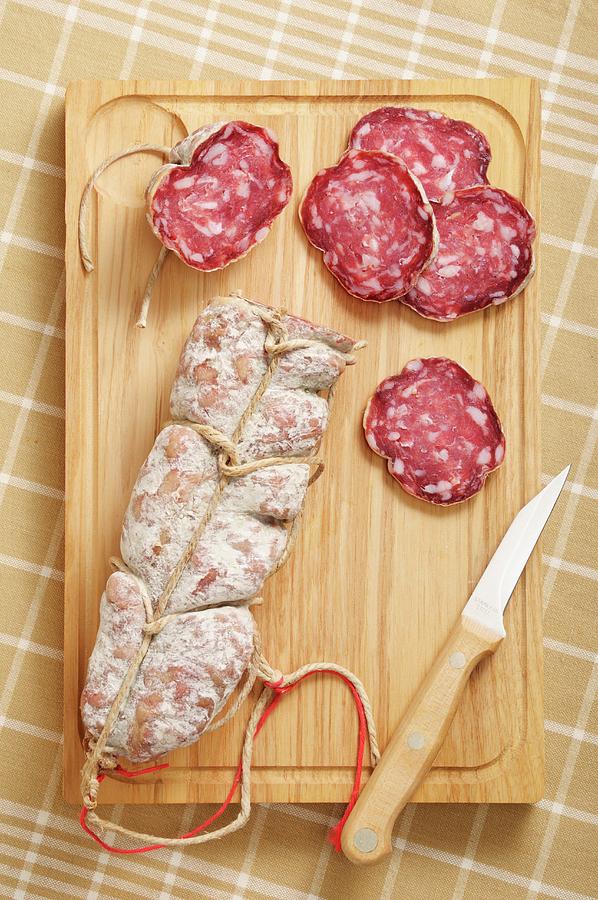 Sliced And Whole Salami On Cutting Board With Knife Photograph by Jean-christophe Riou