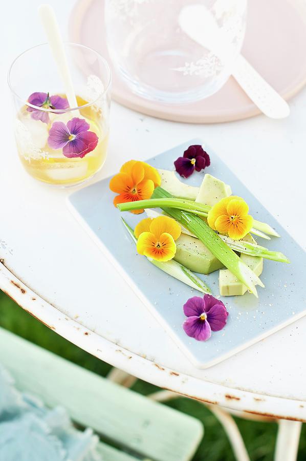 Sliced Avocado Arranged With Spring Onions And Viola Flowers Photograph by Cornelia Weber