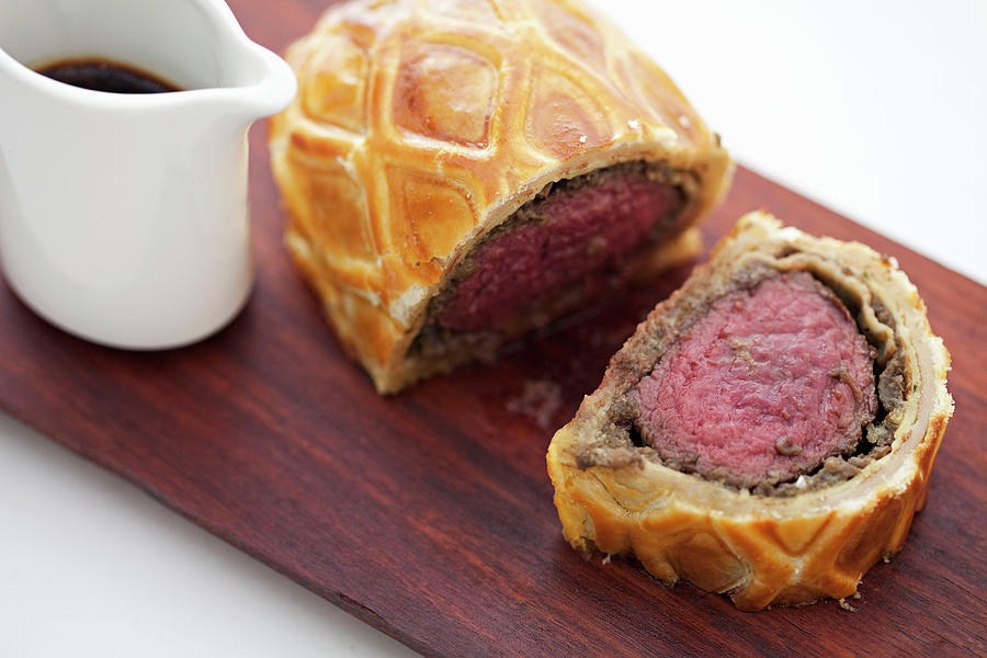 Sliced Beef Wellington On A Wooden Board With A Jus Photograph by Steven Joyce