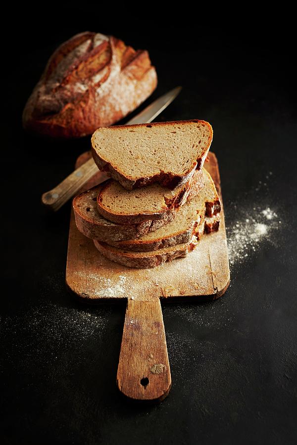 Sliced Bread On A Wooden Board Photograph by Kai Schwabe