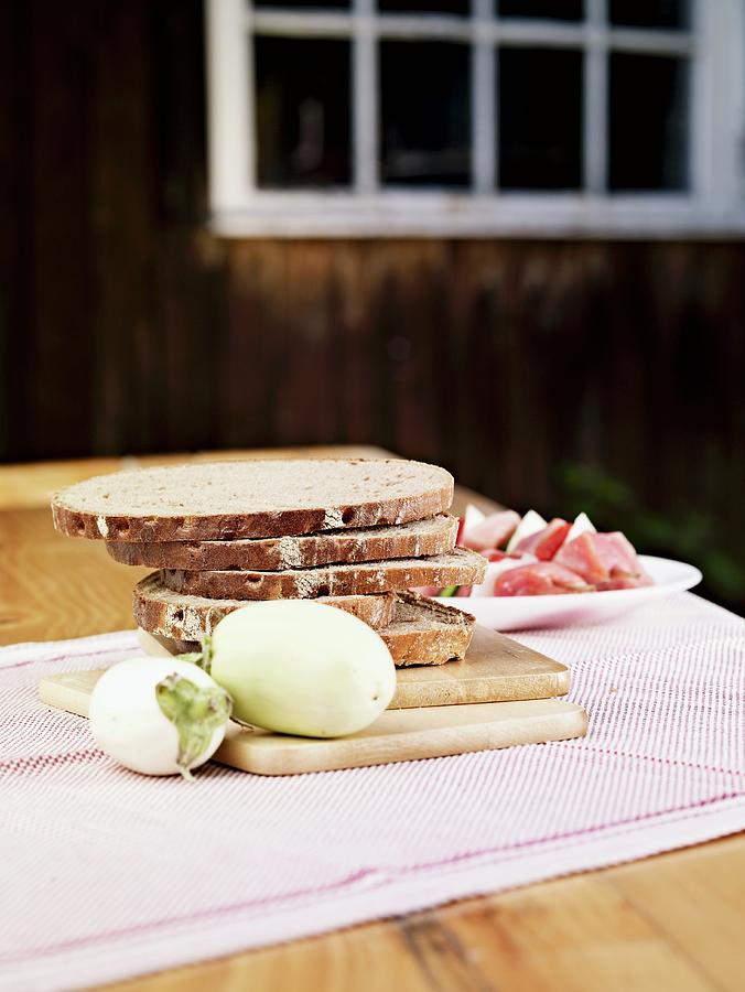 Sliced Rye Bread, White Aubergines And Raw Ham On A Table Photograph by Till Melchior