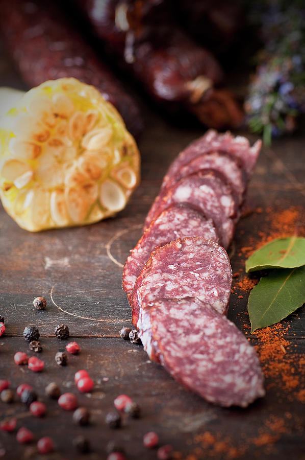 Sliced Venison Sausage With Garlic And Peppercorns On A Wooden Chopping Board Photograph by Tomasz Jakusz