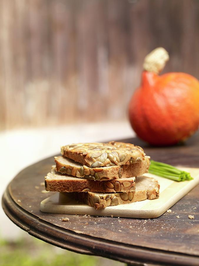 Slices Of Pumpkin Seed Bread, Stacked, On A Rustic Garden Table Photograph by Till Melchior