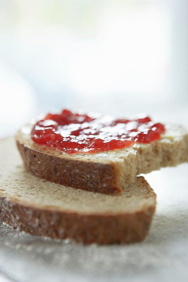 Slices Of Rye Bread Spread With Jam With A Bite Taken Out Photograph by Till Melchior