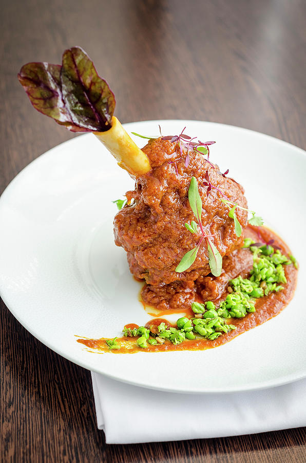 Slow Cooked Lamb Shank In A Rich Tomato, Yogurt, Turmeric And Peas Sauce On A White Plate And Wooden Background Photograph by Giulia Verdinelli Photography