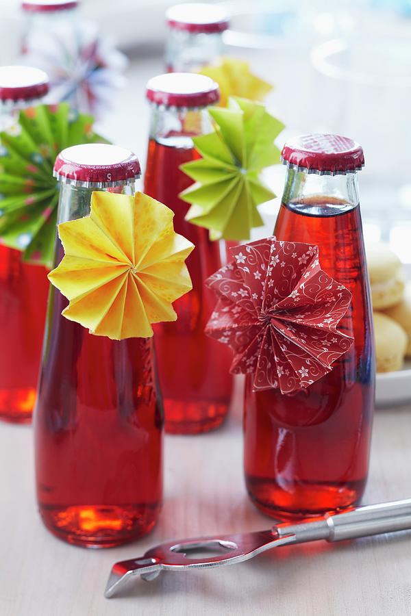 Small Bottles Of Cherry Drinks With Paper Rosettes Photograph by Franziska Taube