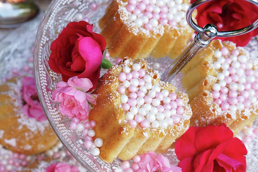 Small Bundt Cakes With Sugar Pearls And Flower Decoration On A Tiered Cake Stand Photograph by Angelica Linnhoff
