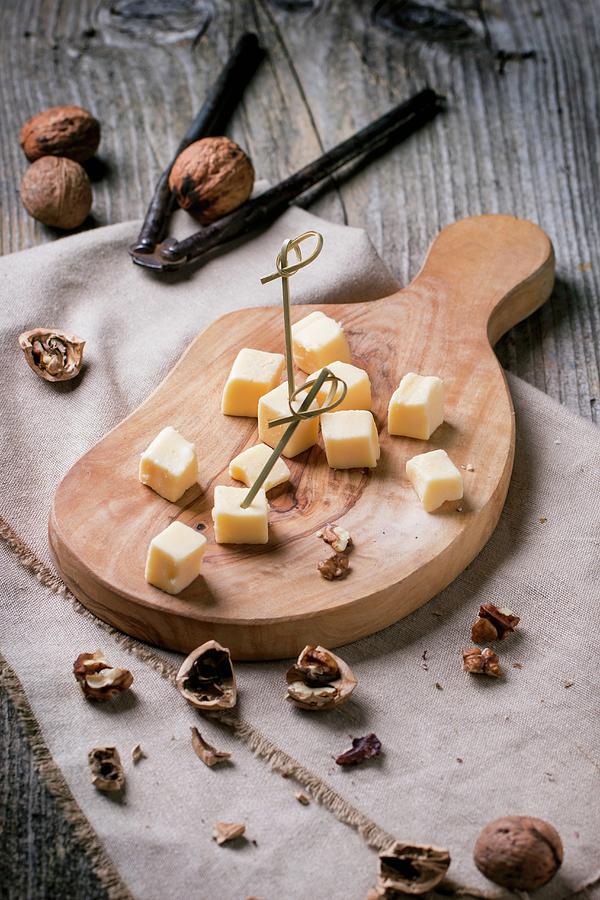 Small Cubes Of Cheese On An Olive Wood Chopping Board With Walnuts Photograph by Natasha Breen
