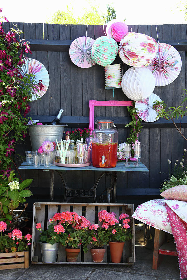 Small Drinks Table With Lanterns And Geraniums In Garden Photograph by Simon Scarboro Fine Art