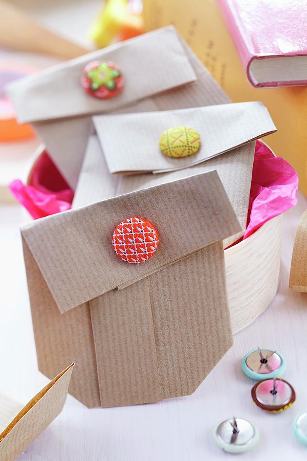 Small Gift Bags Folded From Brown Paper And Held Closed With Button Clips Photograph by Franziska Taube