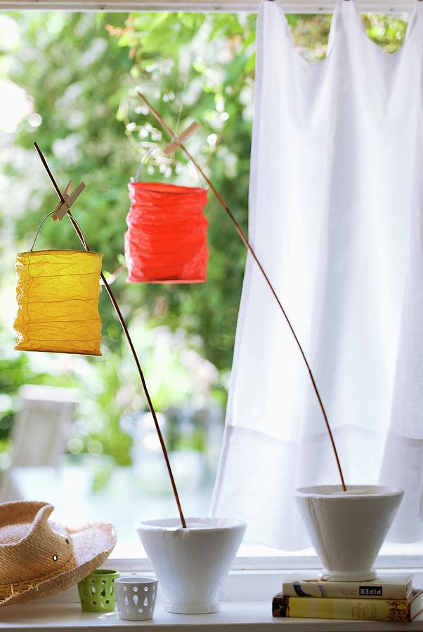 Small Paper Lanterns Attached To Wooden Canes With Clothes Pegs In Garden Setting With White Curtain In Background Photograph by Matteo Manduzio