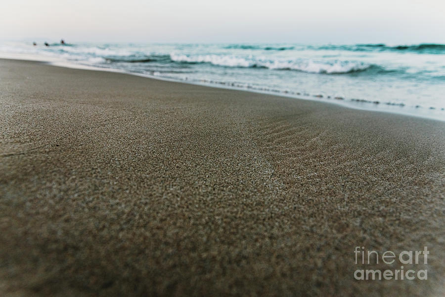 Small waves reach the shore of a serene beach and wet the fine sand, background of tranquility and vacations, at sunset. Photograph by Joaquin Corbalan