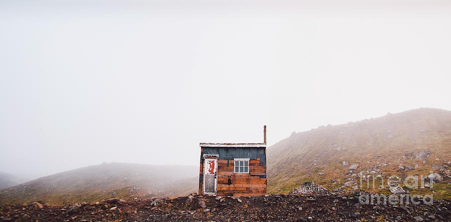 Small wooden hut on top of a mountain surrounded by fog in winter to seek solitude. Photograph by Joaquin Corbalan