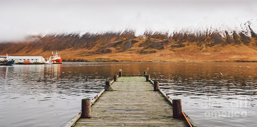 Small wooden pier centered on a lake, facing a snowy mountain. Photograph by Joaquin Corbalan