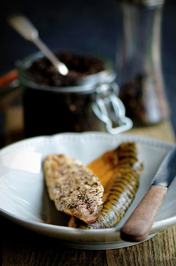 Smoked Peppered Mackerel Fillets In Front Of A Jar Of Peppercorns Photograph by Jamie Watson