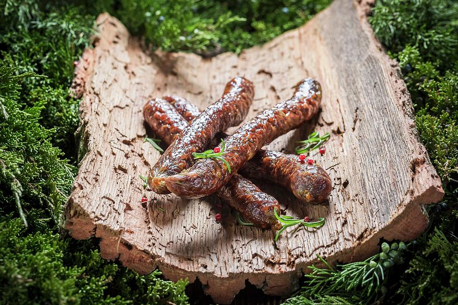 Smoked Sausage With Rosemary On A Piece Of Bark Photograph by Shaiith