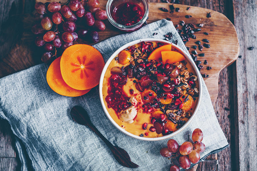 Smoothie Bowl With Kaki, Papaya, Pomegranate Seeds, Grapes, Cacao Nibs, Raspberry Compote, Granola And Physalis Photograph by Freistyle