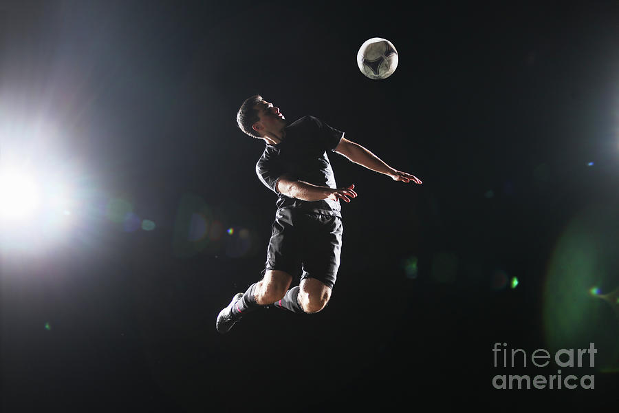 Soccer Player Jumping To Ball On Dark Photograph by Stanislaw Pytel