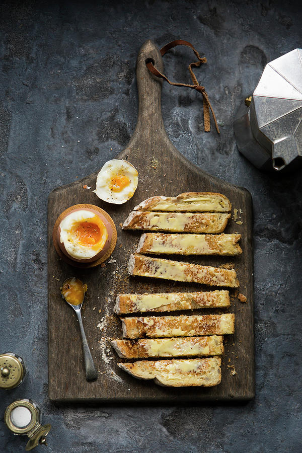 Soft Boiled Dippy Egg With Toasted Soldiers On A Wooden Board And Moody Trendy Setting Photograph by Stacy Grant