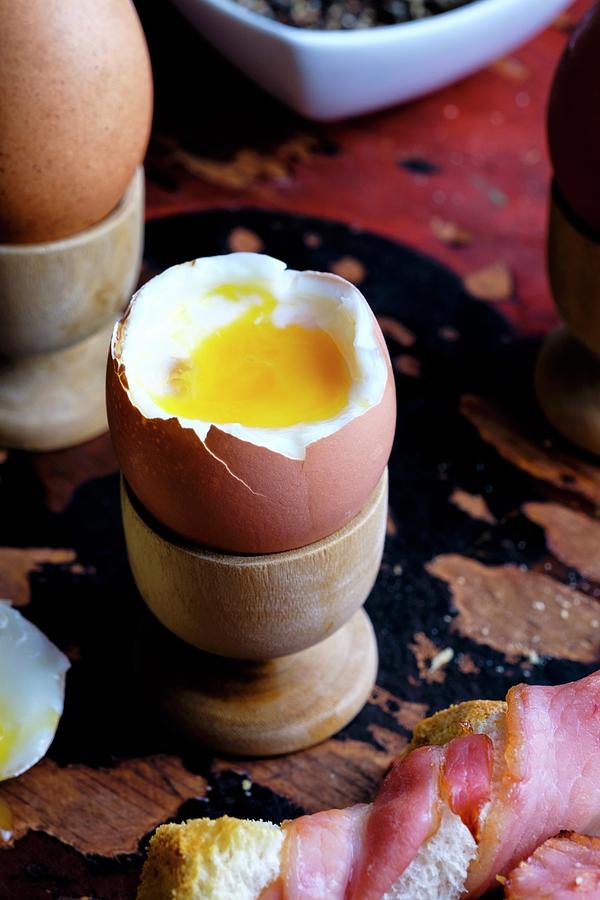 Soft Boiled Eggs With Bacon-wrapped Toast Photograph by Adrian Britton