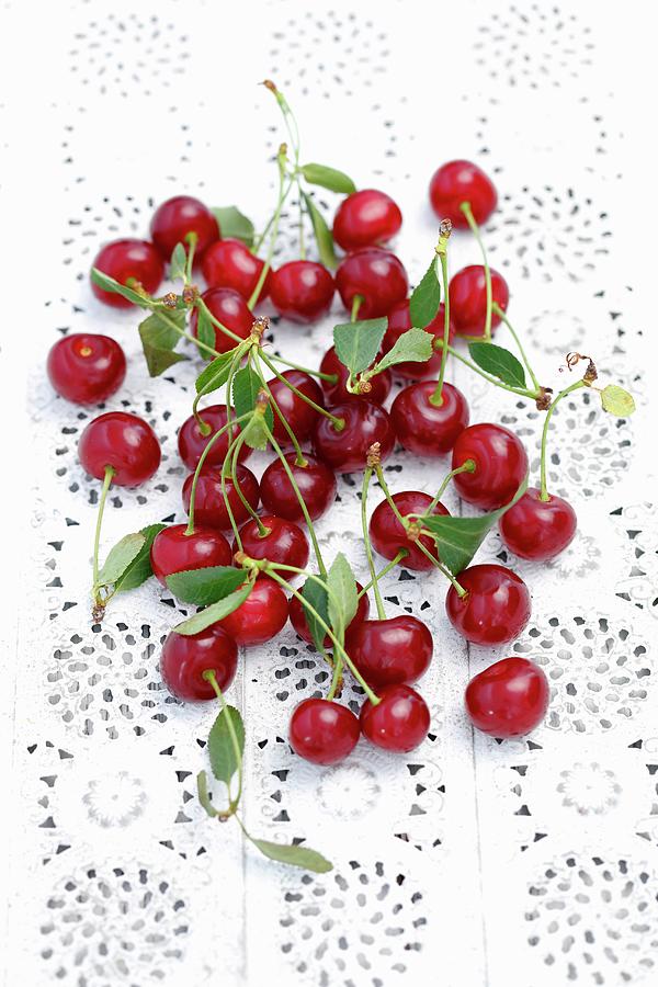 Sour Cherries With Leaves On A Lace Surface Photograph by Rua Castilho