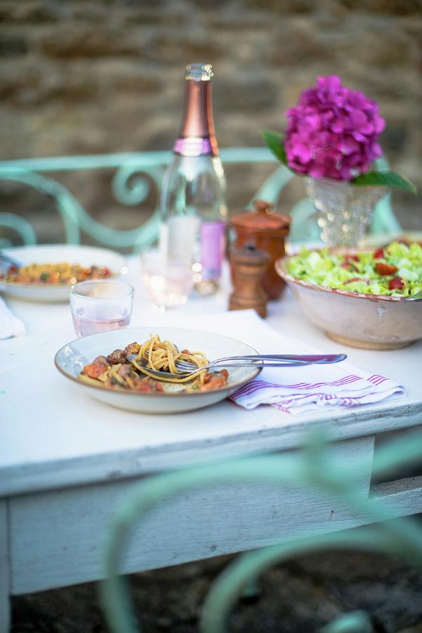 Spaghetti With Meatballs On Plates And A Bowl Of Green Salad On A White Terrace Table Photograph by Sebastian Schollmeyer