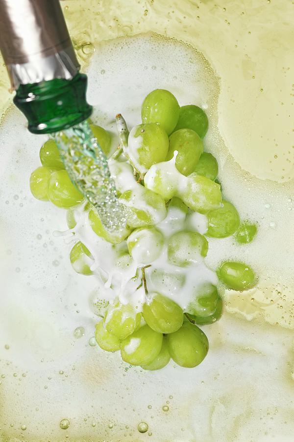 Sparkling Wine Being Poured Over Green Grapes Photograph by Krger & Gross