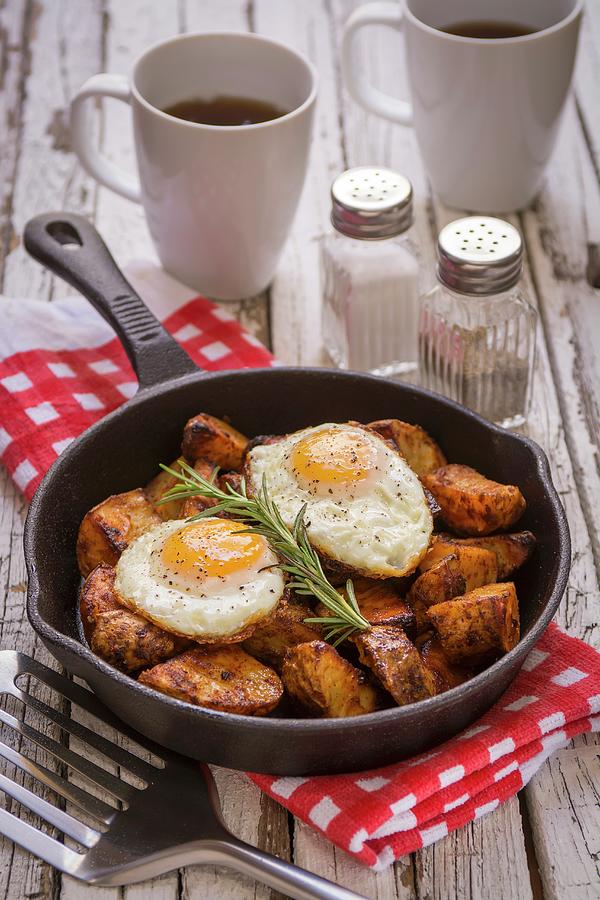 Spiced Baked Potatoes With Fried Eggs And Rosemary In A Cast Iron Pan Photograph by Brian Enright