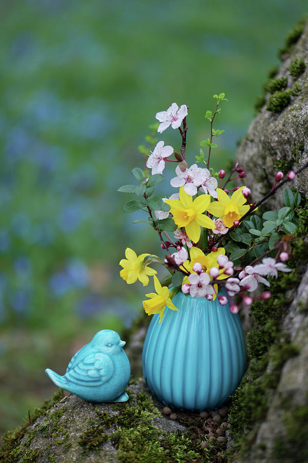 Spring Bouquet Of Daffodils, Blood Plum, And Boxwood In A Turquoise Vase Next To A Ceramic Bluebird Decoration Photograph by Angelica Linnhoff