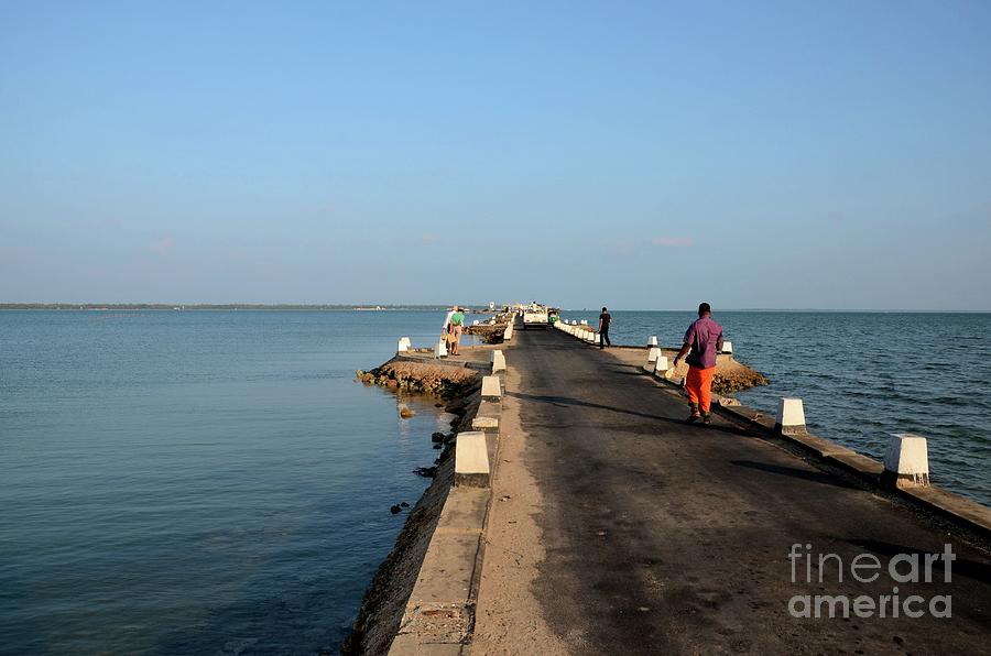 Sri Lankans walk on a causeway road out towards a jetty in water Jaffna Sri Lanka Photograph by Imran Ahmed