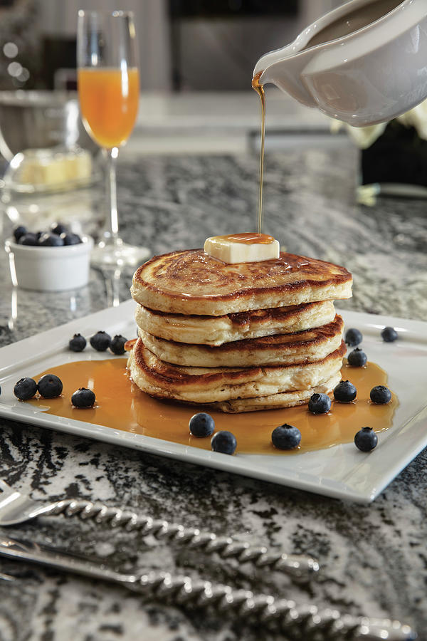 Stack Of Blueberry Buttermilk Pancakes With Butter Adn Syrup Being Poured, Paired With Mimosa Photograph by Cindy Haigwood
