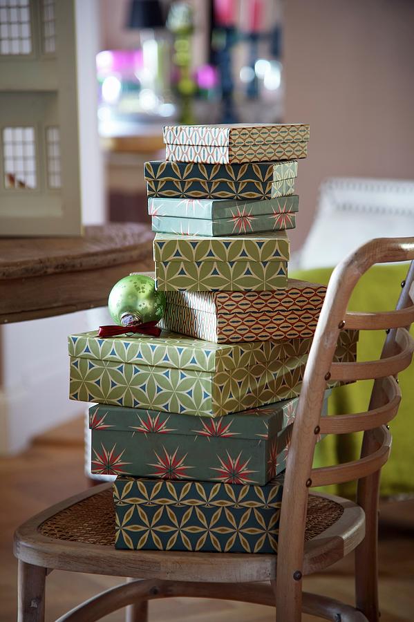 Stack Of Boxes In Retro Patterns On Wooden Thonet Chair Photograph by Winfried Heinze