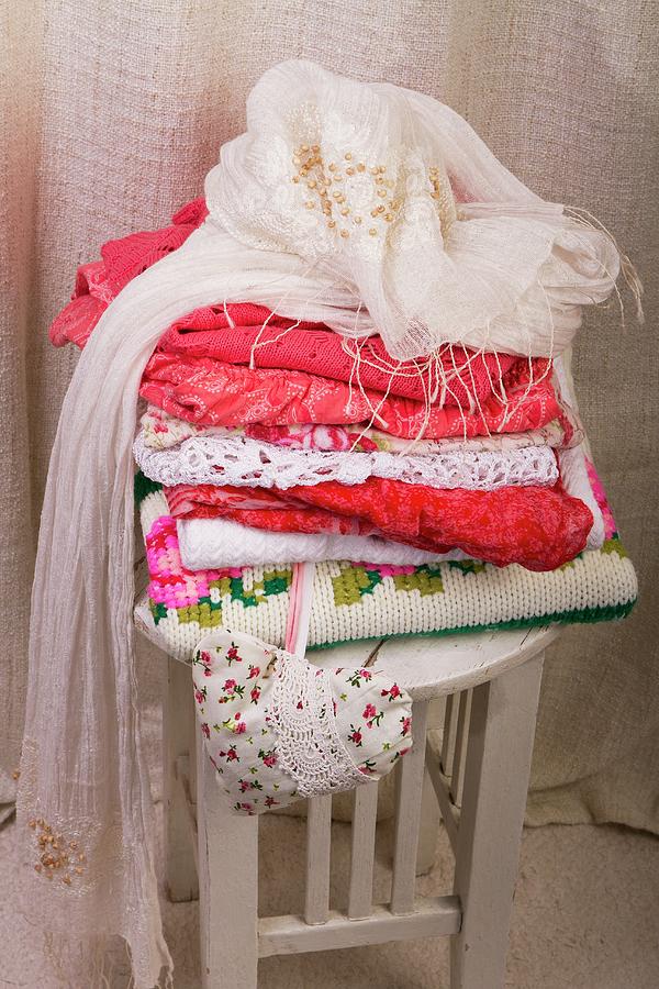 Stack Of Clothes, Scarf And Fabric Heart On Wooden Stool Photograph by Monika Halmos
