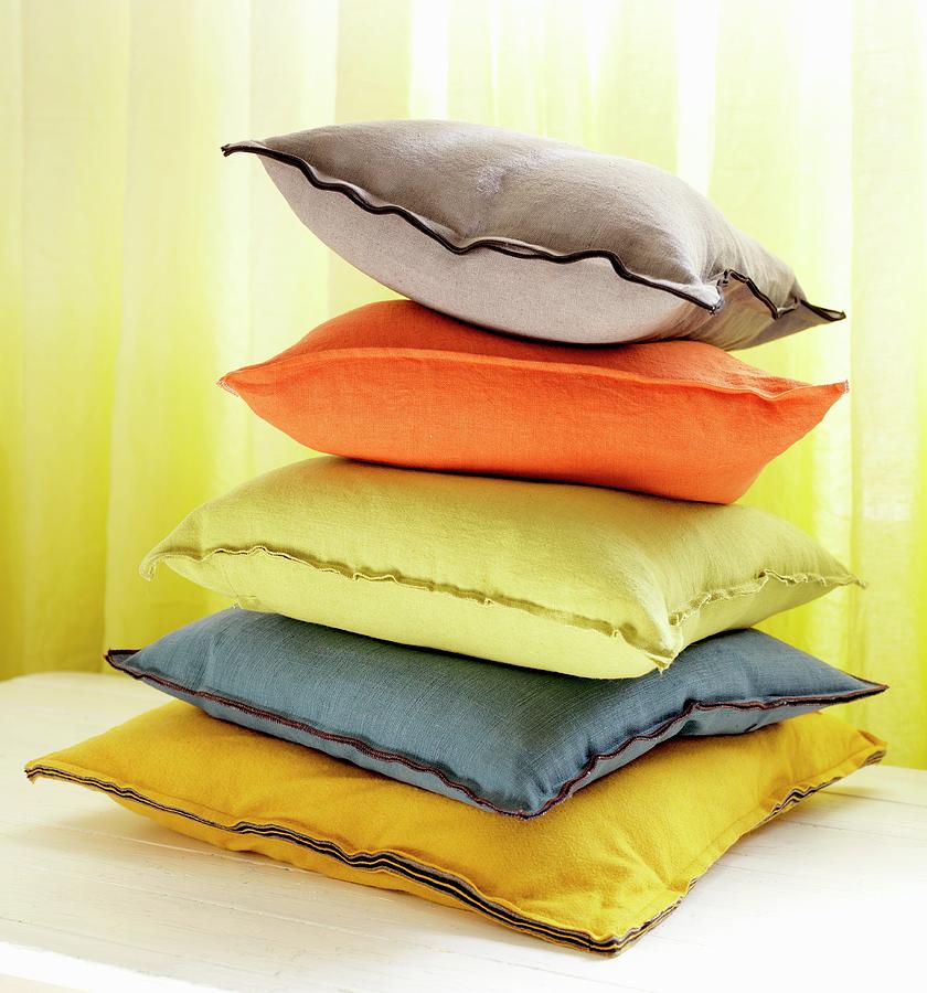 Stack Of Colourful Cushions In Front Of Yellow Curtain Photograph by Anderson Karl