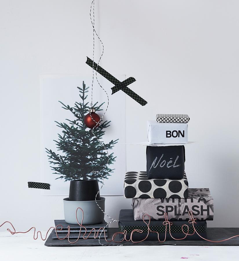 Stack Of Gifts Wrapped In Black And White Paper Next To Printed Picture Of Christmas Tree Photograph by Andreas Hoernisch