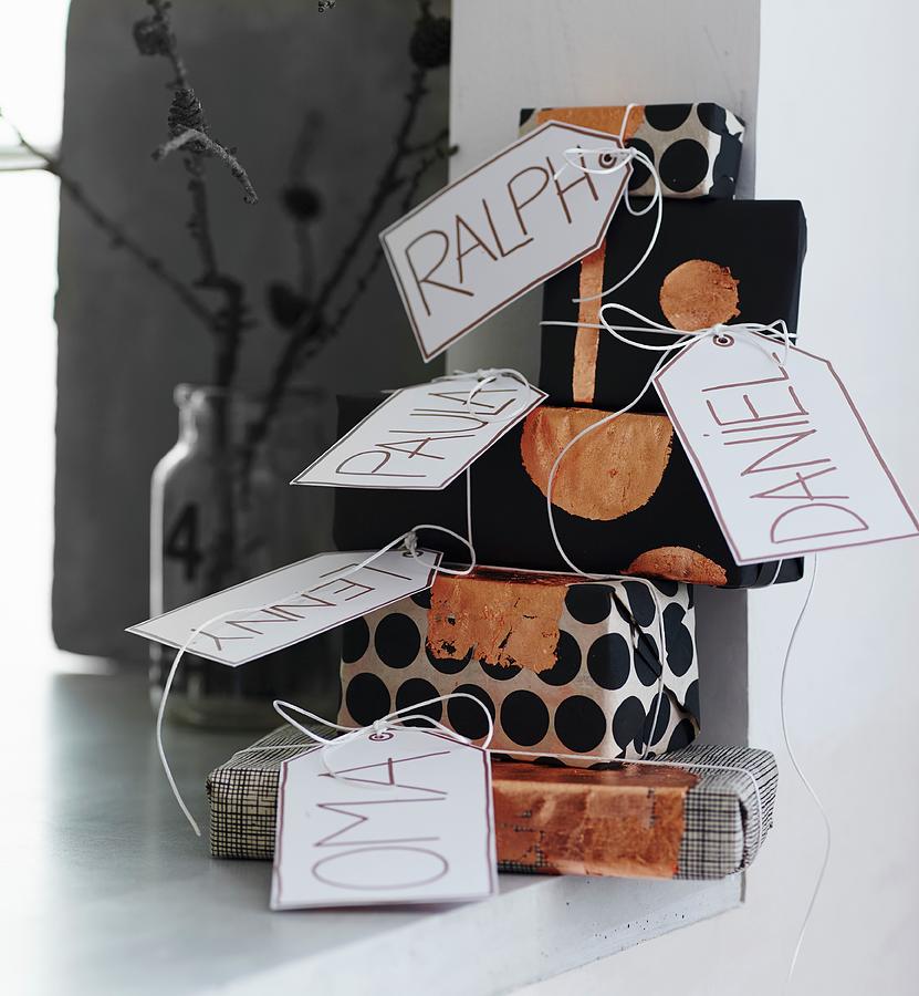 Stack Of Gifts Wrapped In Black And White Paper With Copper Accents And Name Tags Photograph by Andreas Hoernisch