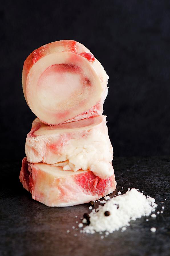 Stack Of Raw Marrow Bones Next To A Pile Of Fleur De Sel And Pepper Photograph by Jamie Watson