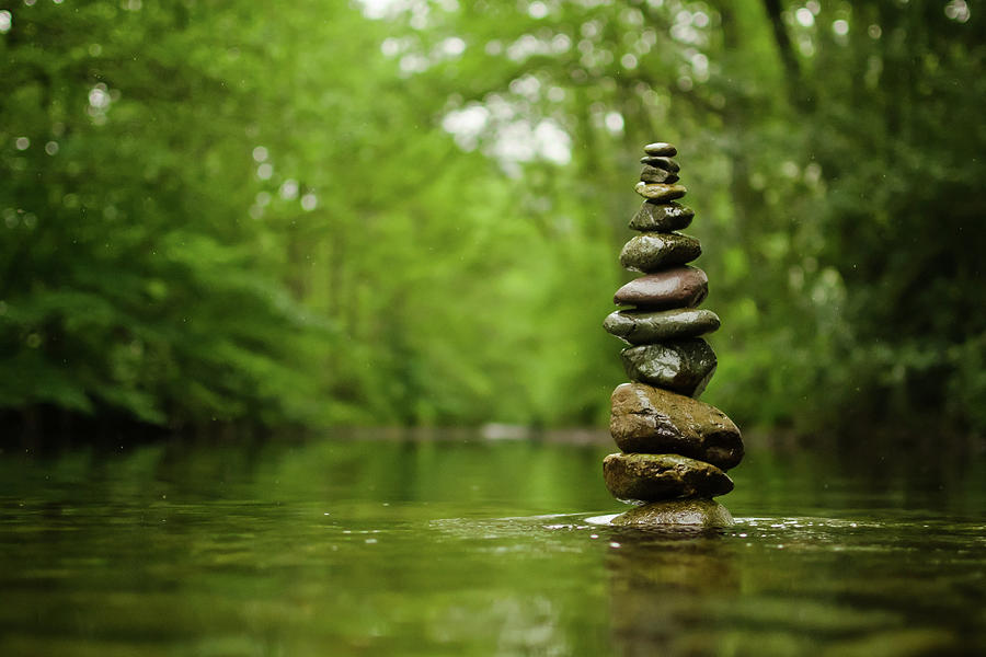 Stack Of River Stones In Placid Water by Colin Mcdonald