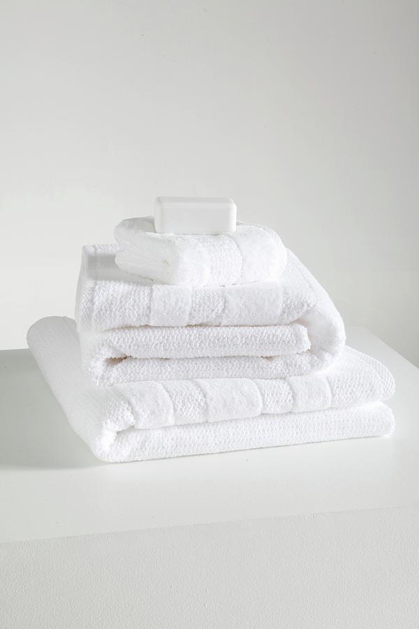 Stack Of White Towels On A White Shelf Photograph by Simon Scarboro