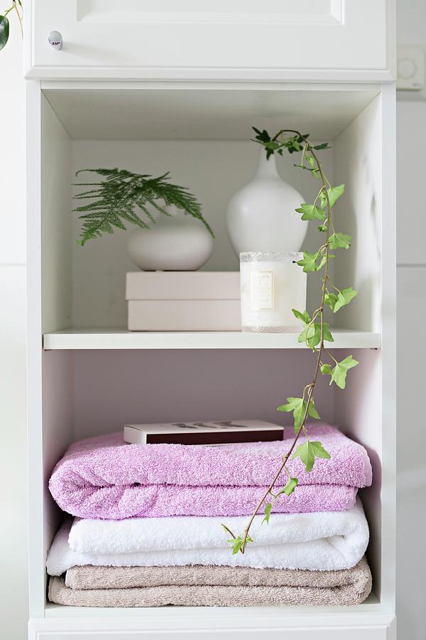 Stacked Towels And Foliage In White Vases On Bathroom Shelves Photograph by Cecilia Mller